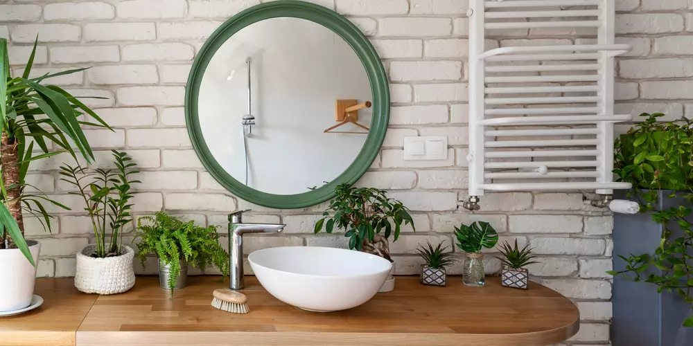 Banheiro com decoração natural, plantas, espelho verde e toque de frescor, ideal para um ambiente com estilo ecológico e relaxante.