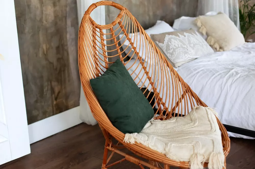 Cadeira de design em vime com acabamento natural, decorada com almofada verde, refletindo estilo Brazilcore na decoração, valorizando matérias-primas brasileiras.