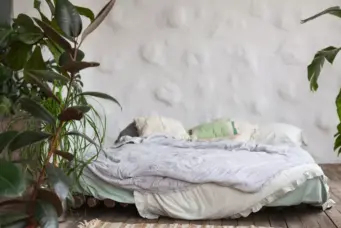 Cama tatame confortável com plantas ao redor, tema de decoração minimalista e aconchegante.