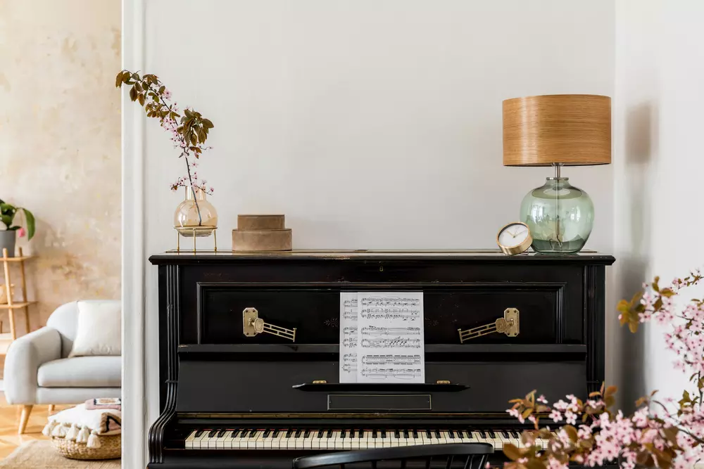 Decoração com instrumentos musicais, destacando um piano preto decorado com partitura e enfeites florais.