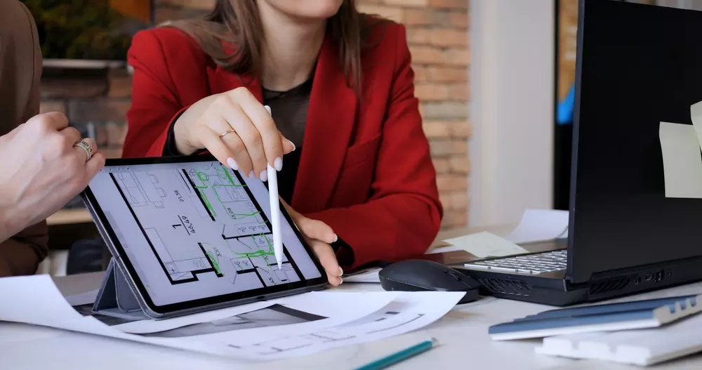 Profissional de arquitetura analisando projeto digital em tablet.