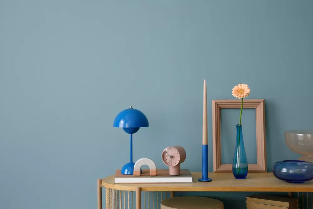 Decoração moderna em tons de azul pastel destacando a cor do ano Pantone 2026, com objetos decorativos minimalistas e um fundo de parede azul clara.