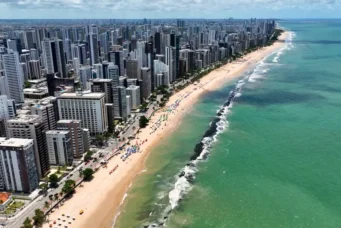 Vista aérea do litoral de uma cidade moderna de Pernambuco, com arranha-céus altos ao longo da orla, praias de areia dourada e mar azul oceano, destacando as melhores cidades de Pernambuco para morar.