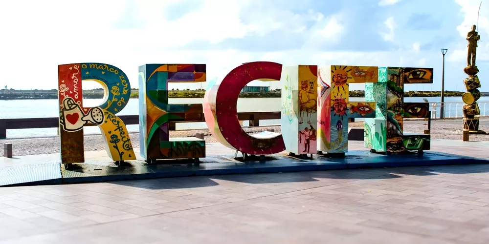 Recife, cidade mais rica de Pernambuco, com a famosa placa decorativa na orla que destaca sua beleza e potencial para quem busca as melhores cidades de Pernambuco para morar.