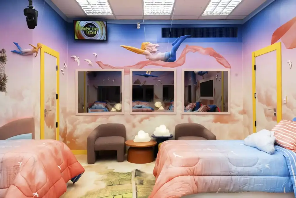 Um dos quartos dos sonhos temáticos do BBB26. Parede temática de anjos voando, camas confortáveis, espelhos e decoração moderna,