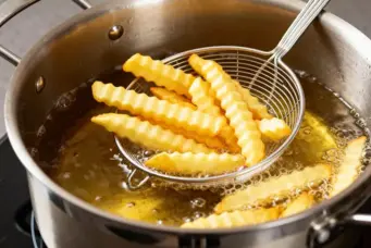 Uma panela com óleo fritando batatas em palitos. Ilustrando matéria sobre eliminar cheiro de fritura da casa.