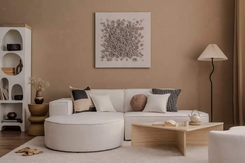 Sala de estar com móveis coloridos, incluindo almofadas em cadeira bege, sofá branco e decoração moderna em um ambiente aconchegante.