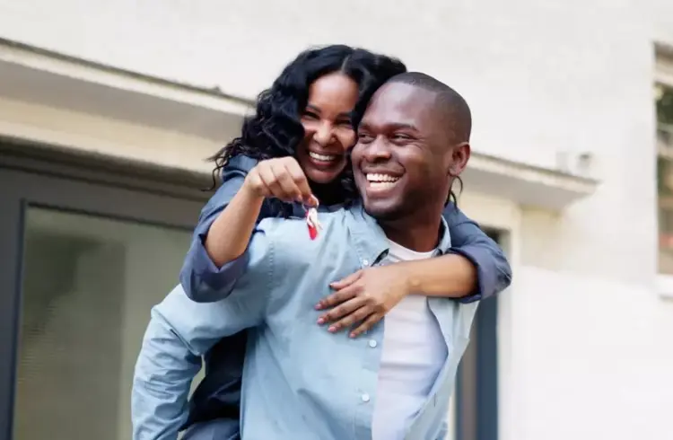 Faixa 4: como planejar a entrada sem travar outros sonhos? Na foto casal feliz segurando as chaves da casa, celebrando a conquista com um sorriso radiante e alegria, simbolizando sucesso e realização.