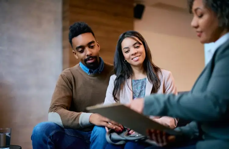 Pessoas discutindo pacto marciano em uma negociação imobiliária, com aparência de confiança e interesse no documento assinado.