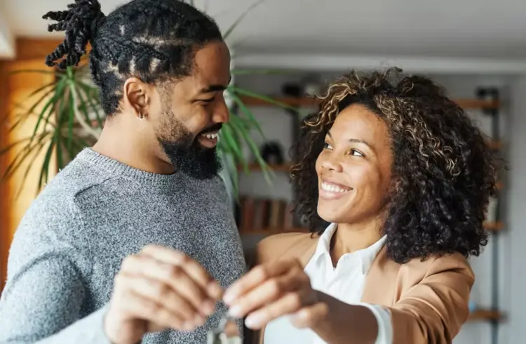 Casal feliz assinando contrato de financiamento conjunto, simbolizando acordo financeiro entre duas pessoas, com sorriso e mãos dadas, em ambiente acolhedor.