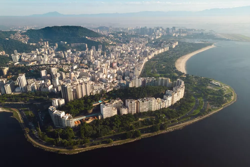 Vista aérea do bairro Flamengo no Rio de Janeiro, com skyline de edifícios, praias e áreas verdes próximas à Baía de Guanabara, mostrando os bairros do Rio.