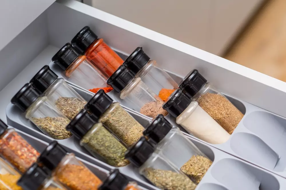 Organizador de potes de temperos diversos dentro de uma gaveta do armário da cozinha.
