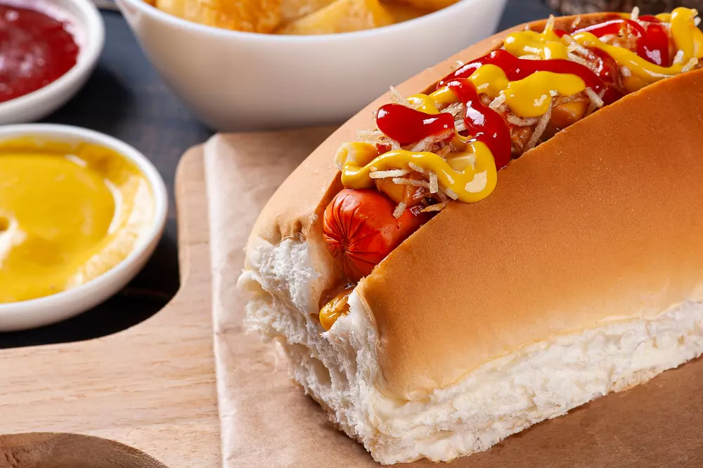 Cachorro-quente com salsicha, batata palha. ketchup, mostarda, e maionese em pão macio, acompanhado de molhos em tigelas, ideal para lanches rápidos. Representando o tradicional Hot Dog Londrinense