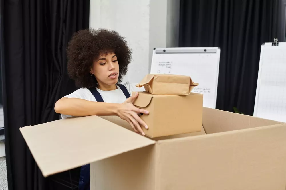 Mulher organizando caixas de papelão durante a aplicação do método 5S, focando no passo de Seiri para eliminar itens desnecessários.