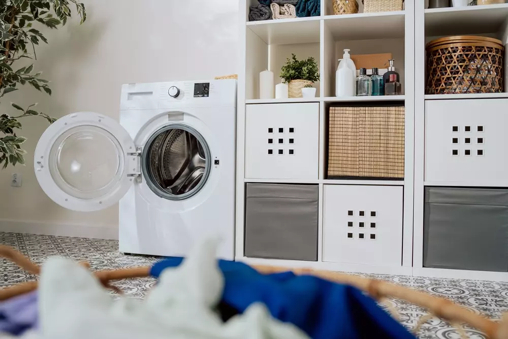 Organização de lavanderia utilizando o Método 5S para manter tudo no seu lugar e otimizar espaço, com máquina de lavar roupa e prateleiras bem organizadas.