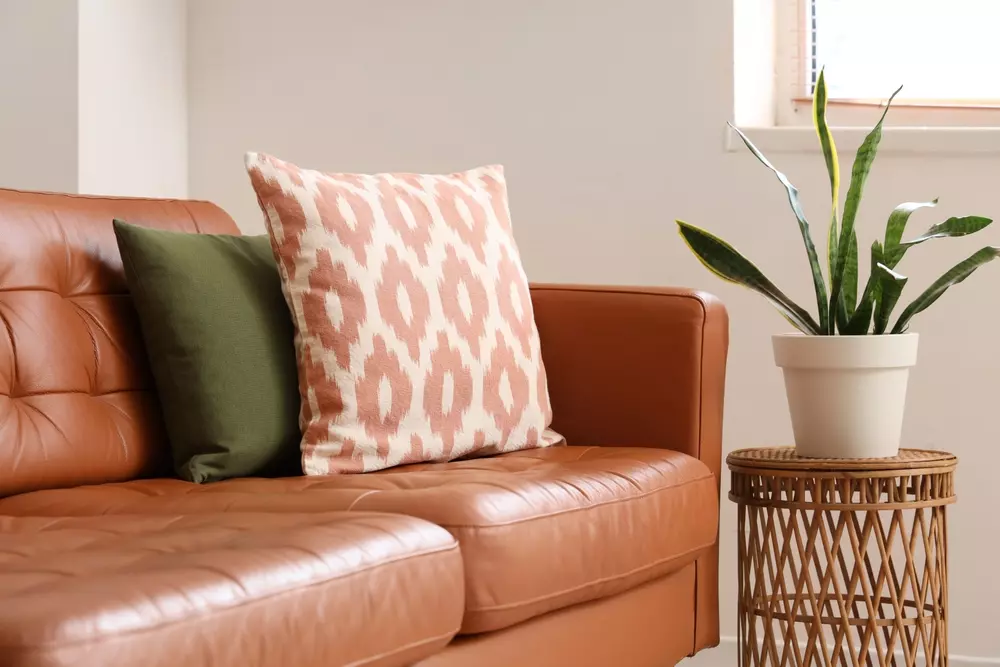 Decoração de sala com sofá de couro, almofadas coloridas e plantas, ideal para ambientes pequenos. Truques para aproveitar espaço usando couro na decoração.