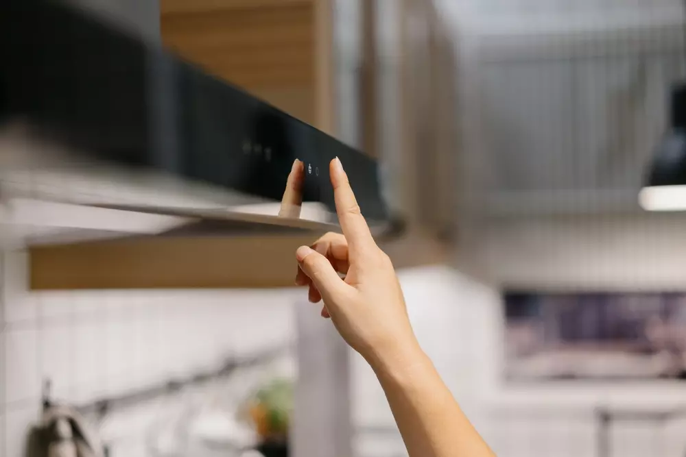 Pessoa utilizando a coifa de cozinha para eliminar cheiro de fritura e manter o ambiente aroma agradável