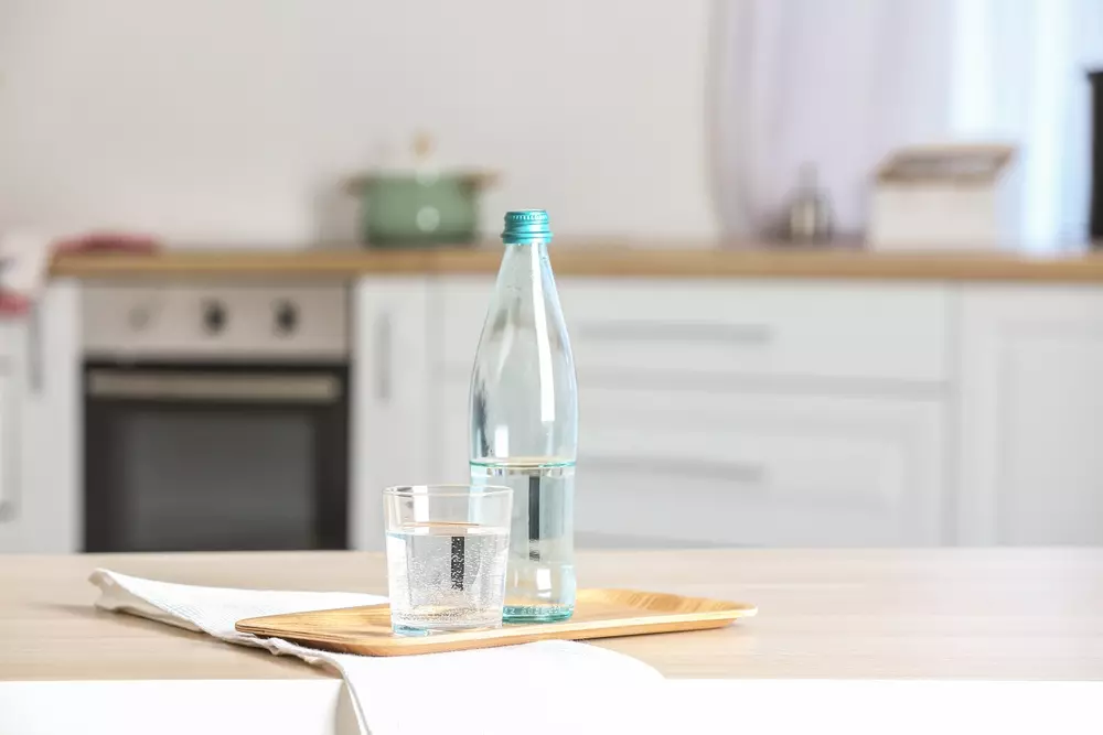 Garrafa transparente contendo líquido translúcido representando a mistura do vinagre com água para eliminar cheiro de fritura.