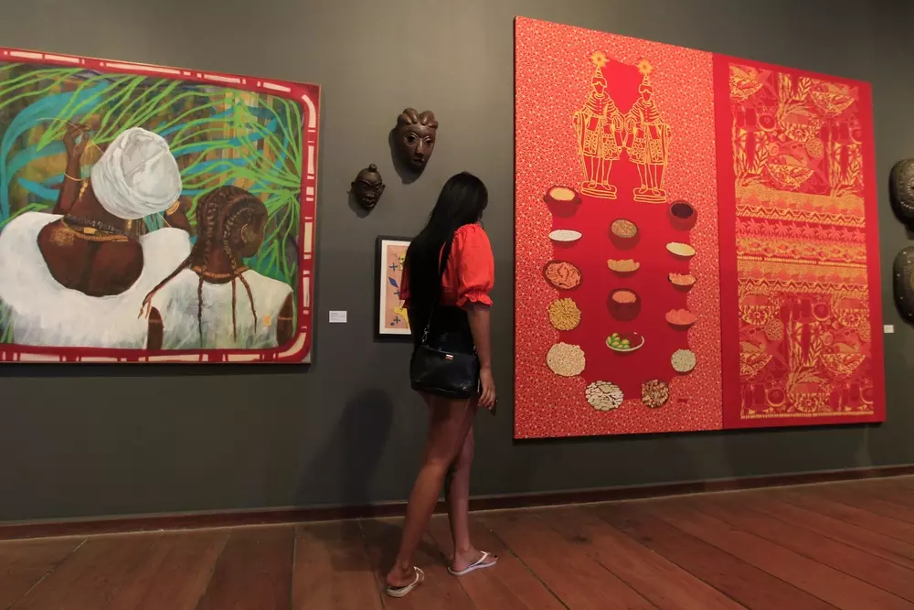 Mulher observando obras de arte africano em uma galeria de museu
