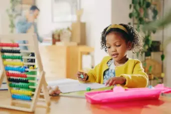 Foto trazendo o conceito de decoração educativa, com menina brincando com jogos educativos e brinquedos de matemática em sala de aula infantil moderna, promovendo desenvolvimento cognitivo e aprendizado divertido