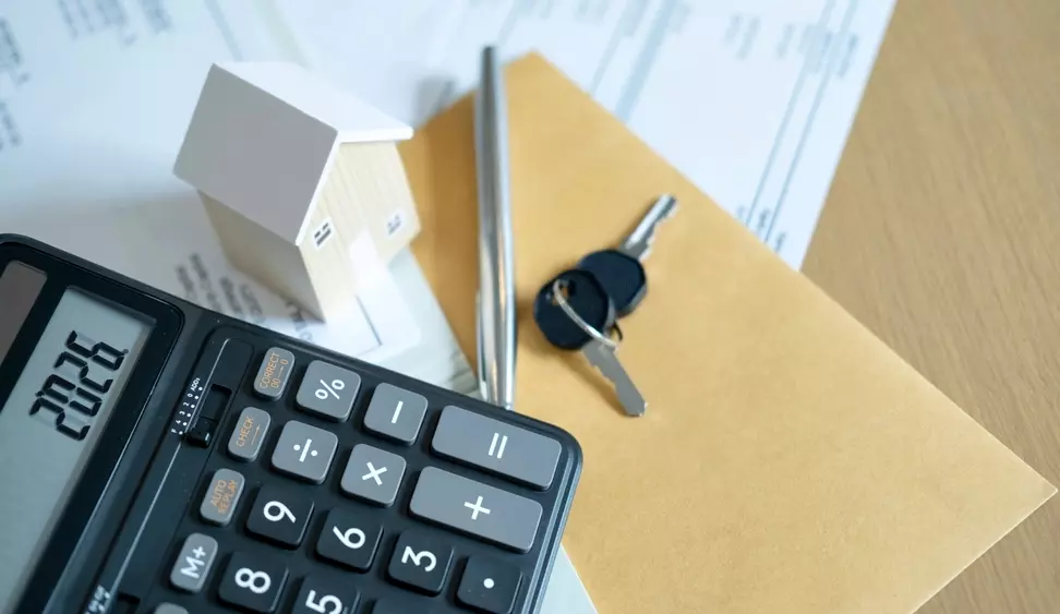 Documentos, chave, miniatura de casa, calculadora e envelope de papel relacionados ao programa Minha Casa Minha Vida faixa 4, utilizados para cálculos e planejamento de financiamento imobiliário.