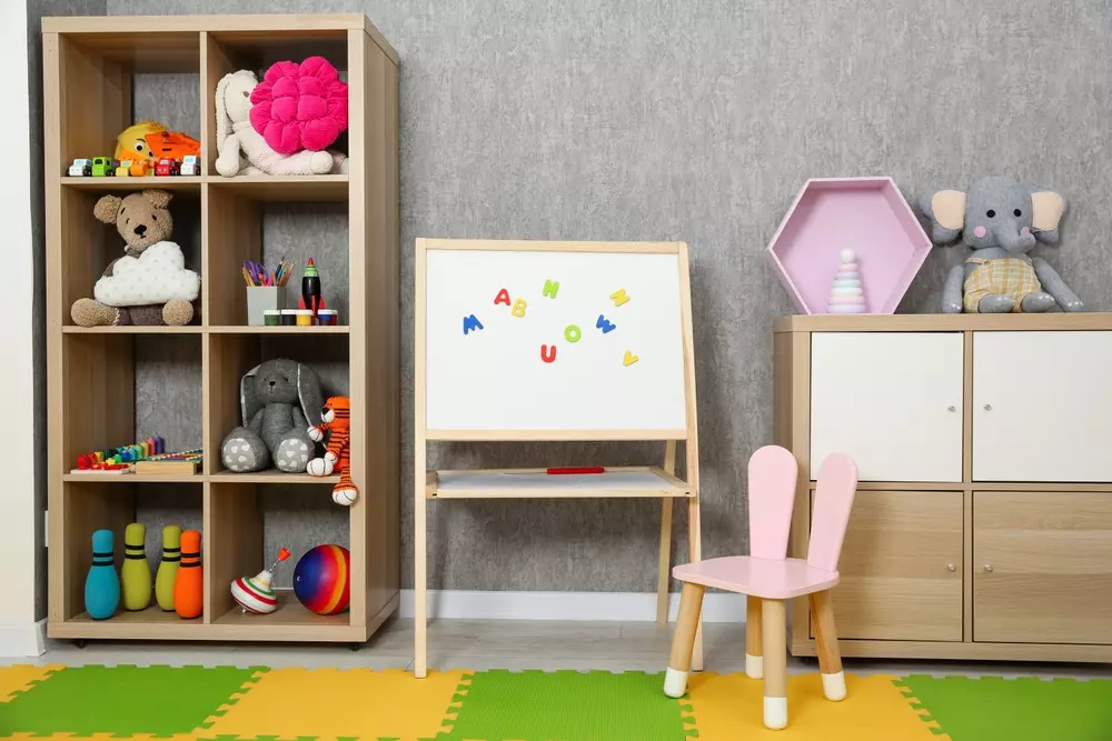 Organização de decoração educativa com prateleiras com brinquedos, quadro branco com letras, e móveis infantis em ambiente residencial