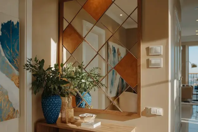 Corredor com espelho decorativo na parede, refletindo parte da sala de estar, com detalhes em madeira e plantas verdes ao lado