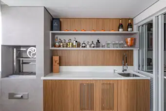 Projeto da arquiteta Cristiane Schiavoni mostrando um bar embutido em uma cozinha da área gourmet.